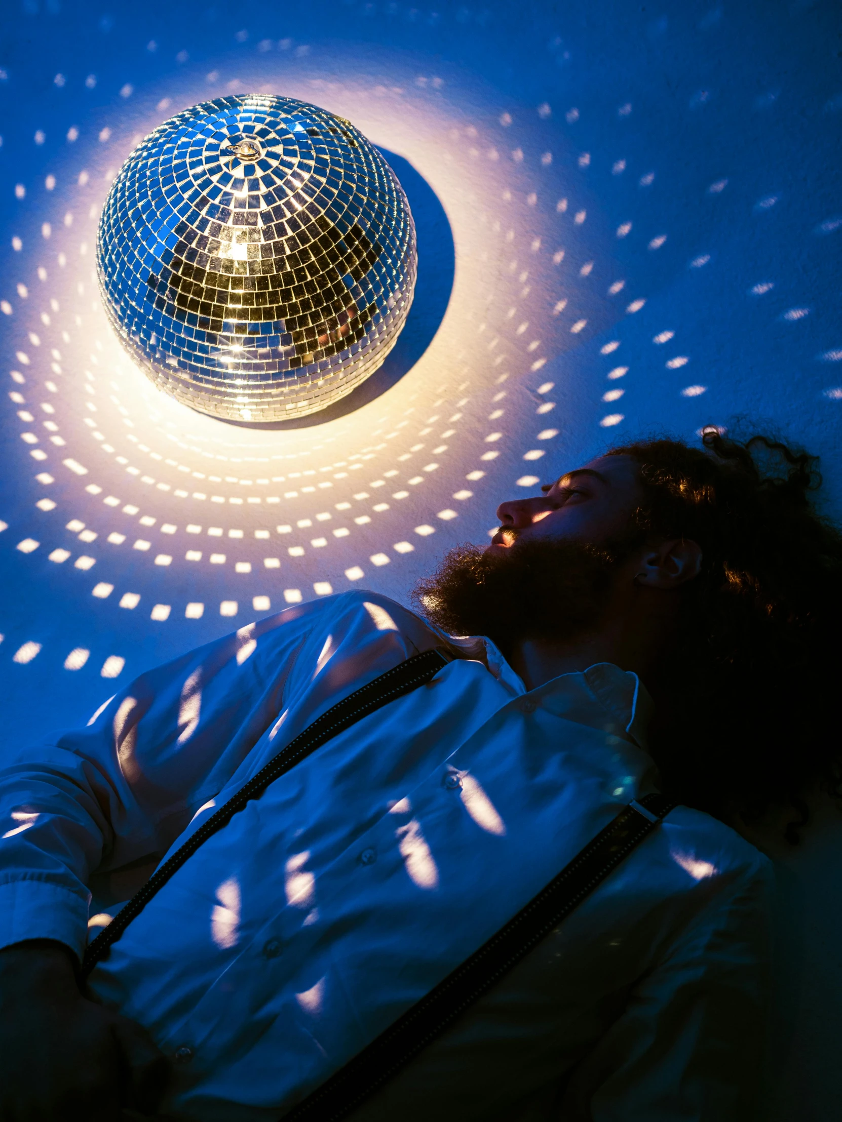 a man laying down next to a disco ball, by Julia Pishtar, bearded, mood light, 3 0 0 mm, full colour