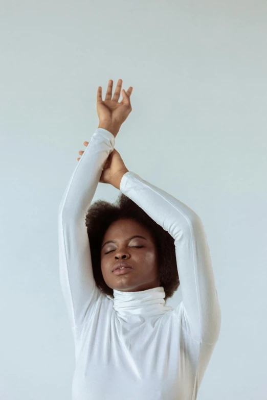 a woman in a white shirt is doing yoga, by Carey Morris, wearing turtleneck, afrocentric mysticism, hands in her hair, ignant