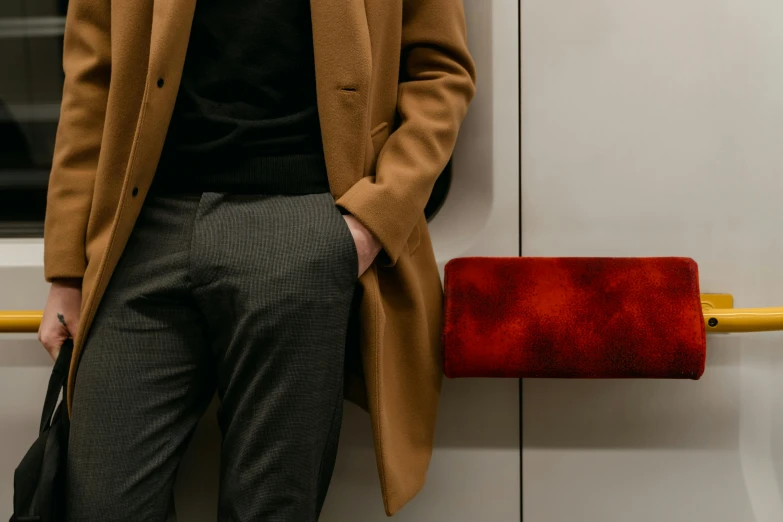 a man standing on a subway with his hands in his pockets, an album cover, by Emma Andijewska, trending on unsplash, bauhaus, red fabric coat, holding a wood piece, detail texture, red tie