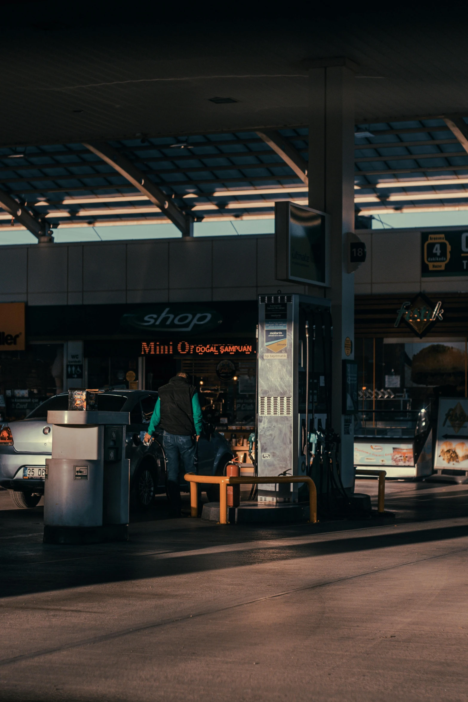 a car is parked in front of a gas station, pexels contest winner, man sitting facing away, airport, late afternoon, square