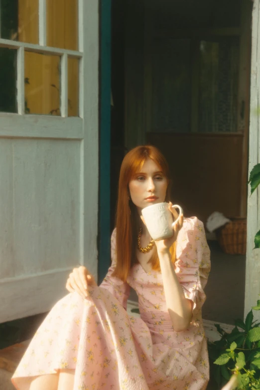 a woman sitting on a porch drinking a cup of coffee, an album cover, by Penelope Beaton, pre-raphaelitism, petra collins, soft red hair, 70mm film screenshot, lily