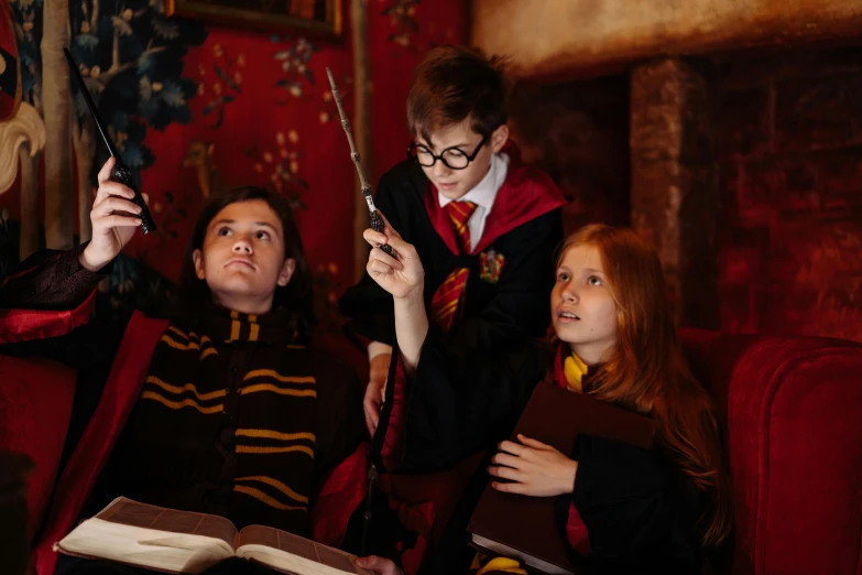 a group of people sitting on top of a red couch, holding wands, magic school uniform, marauders map, close - up photograph