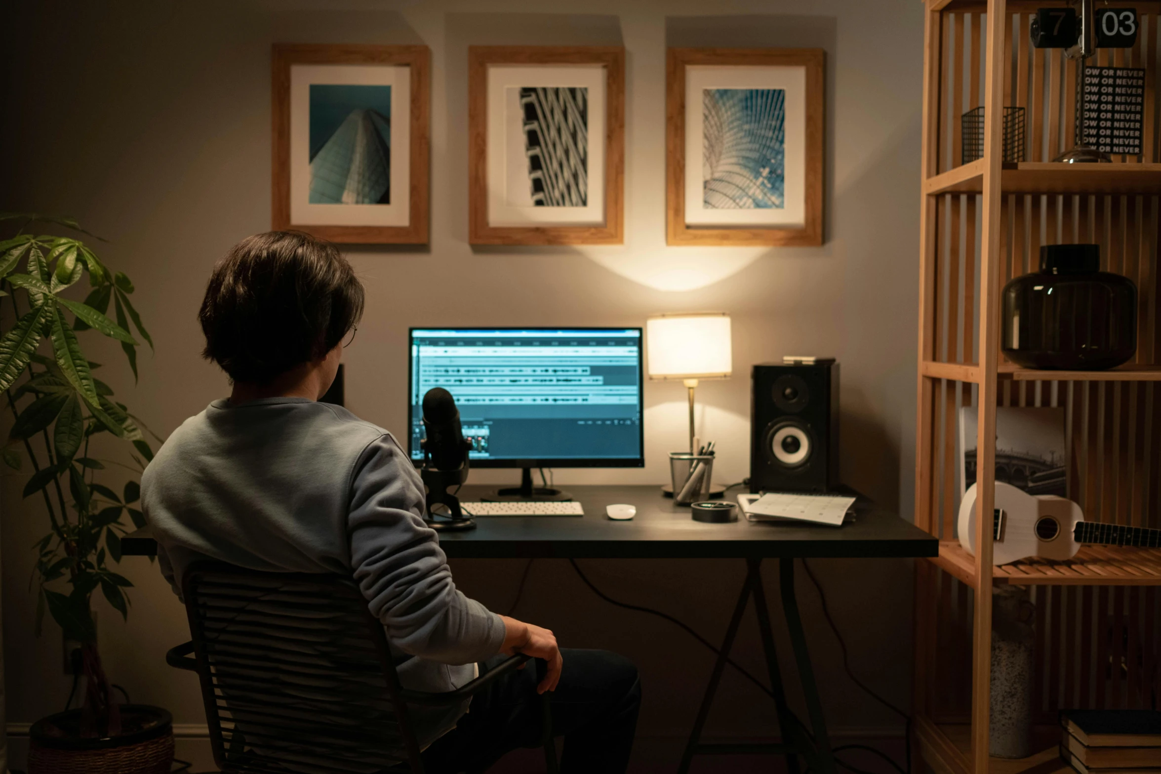 a person sitting at a desk in front of a computer, inspired by Elsa Bleda, pexels contest winner, audio equipments, man sitting facing away, sitting in front of a microphone, in small room
