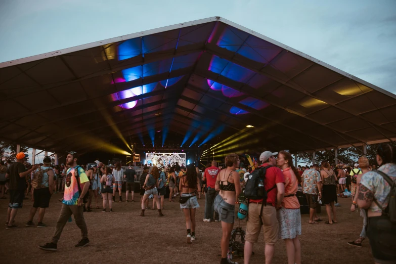 a group of people standing in front of a tent, by Lee Loughridge, unsplash contest winner, process art, music festival, panorama shot, lines of lights, taken at golden hour