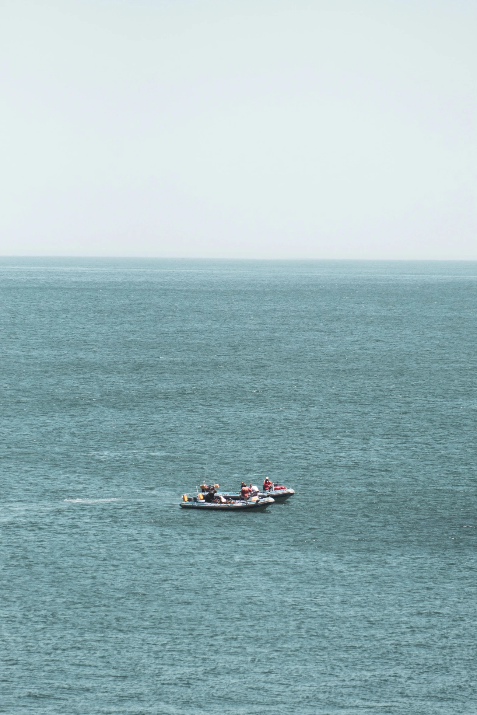 a small boat in the middle of a large body of water, they are very serious, telephoto vacation picture, pembrokeshire, tubes