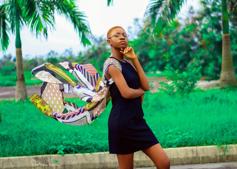 a woman in a black dress talking on a cell phone, inspired by Chinwe Chukwuogo-Roy, pexels contest winner, visual art, elegant tropical prints, cloth head wrap, spreading her wings, casual pose