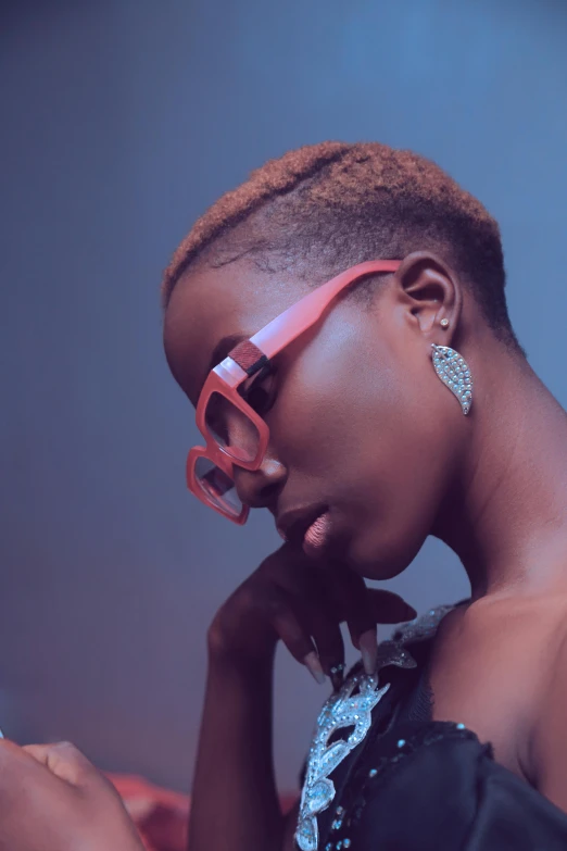 a close up of a person with a cell phone, an album cover, by Lily Delissa Joseph, trending on pexels, afrofuturism, shaved sides short top, pink glasses, elegant profile posing, orange hue