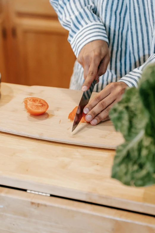 a close up of a person cutting carrots on a cutting board, épaule devant pose, multiple stories, high-quality photo, no crop