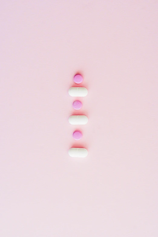 pills arranged in a row on a pink background, by Matteo Pérez, aestheticism, thedieline, back facing, milk, v