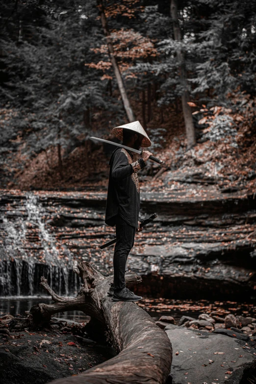 a man standing on a log in the woods, an album cover, pexels contest winner, black pointed hat, zen aesthetic, streams, urban samurai