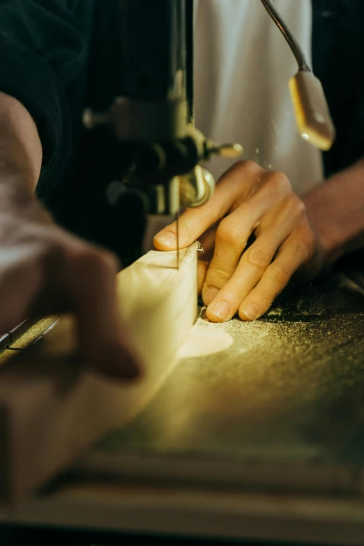 a close up of a person working on a piece of wood, a silk screen, by Jacob Toorenvliet, trending on unsplash, bartending, stitching, holding beer, clamp shell lighting