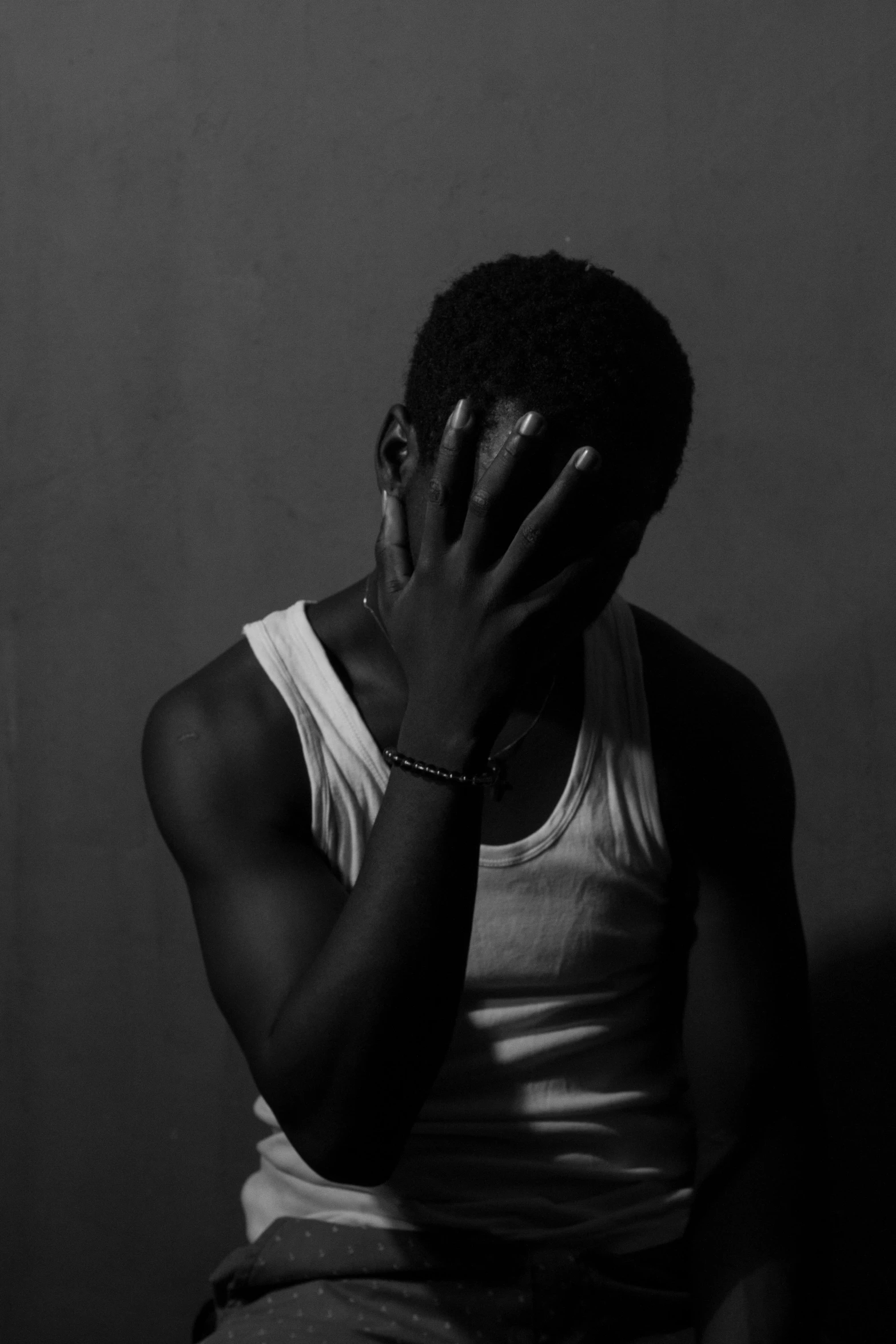 a black and white photo of a man covering his face, a black and white photo, by Nadir Afonso, lil uzi vert, looks sad and solemn, his arms are behind his back, bleed