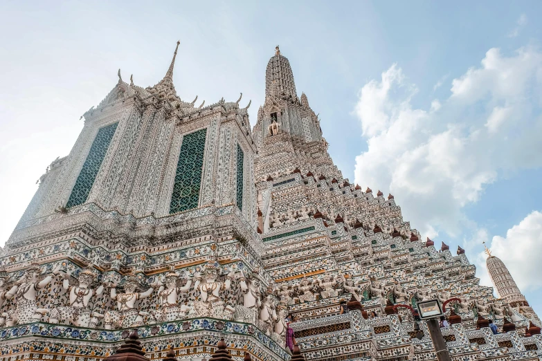 a group of people standing in front of a tall building, thai architecture, ornate tiled architecture, background image, lead - covered spire