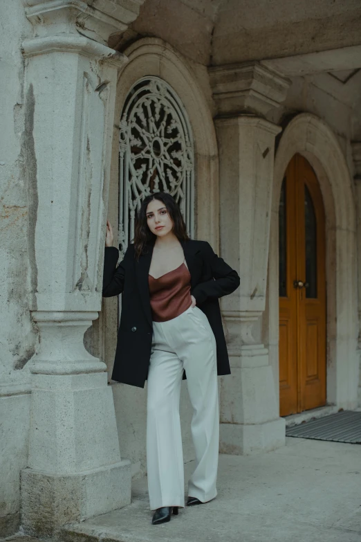 a woman posing for a picture in front of a building, pale skin, archways, wearing elegant casual clothes, trending photo