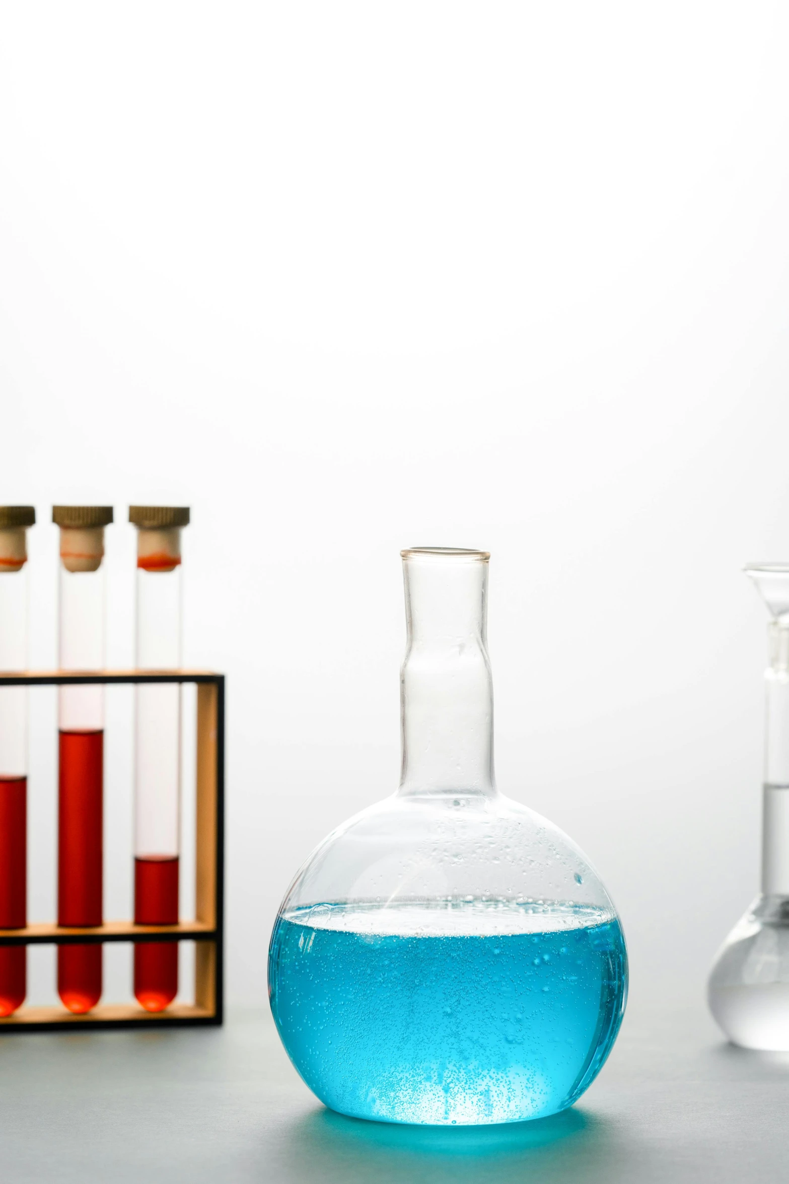 a group of glass flasks sitting on top of a table, test tubes, blue and red color palette, promo image, composite