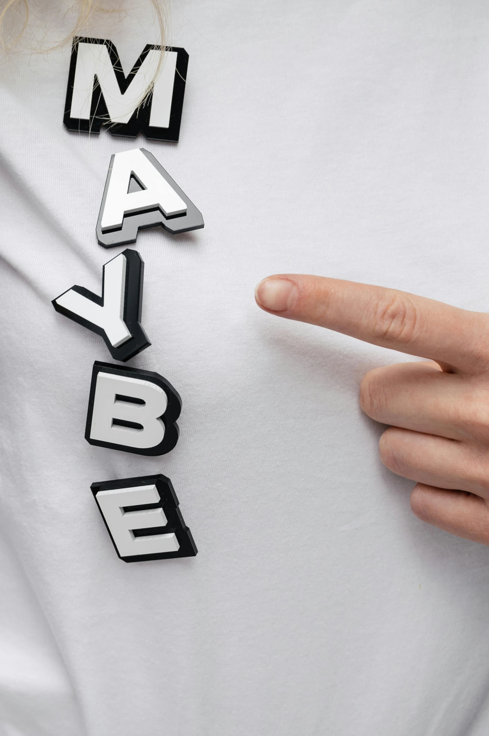 a woman wearing a t - shirt that says maybe, an album cover, inspired by Herbert Bayer, trending on pexels, with index finger, 3 d print, detail shot, babel