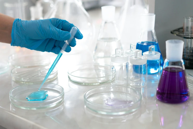 a person in blue gloves holding a pipe in a laboratory, shutterstock, beakers of colored liquid, blue and purple colour scheme, unedited, thumbnail