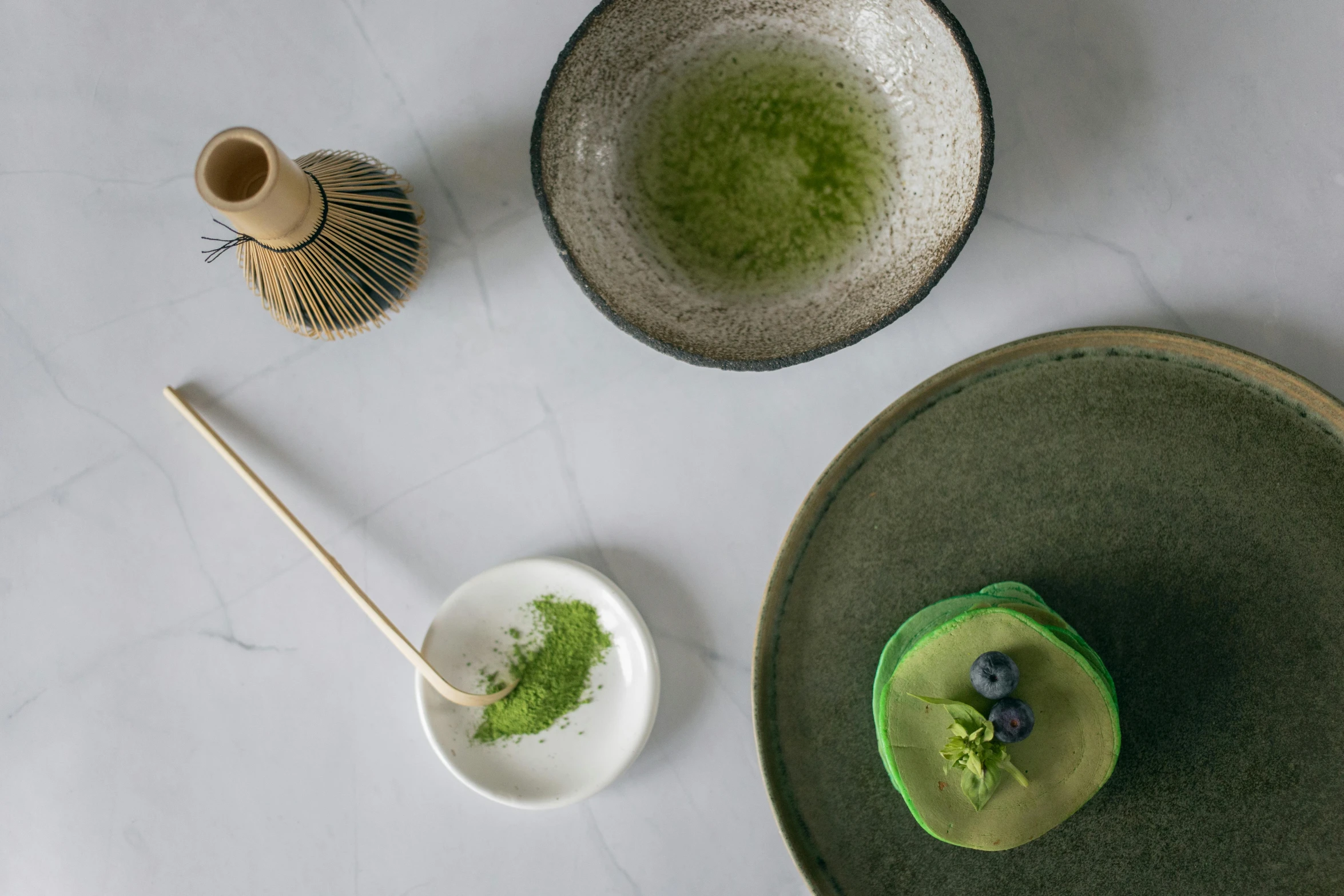 a close up of a plate of food on a table, a still life, inspired by Kanō Shōsenin, trending on unsplash, minimalism, loputyn and matcha, monochromatic green, desserts, looking towards camera