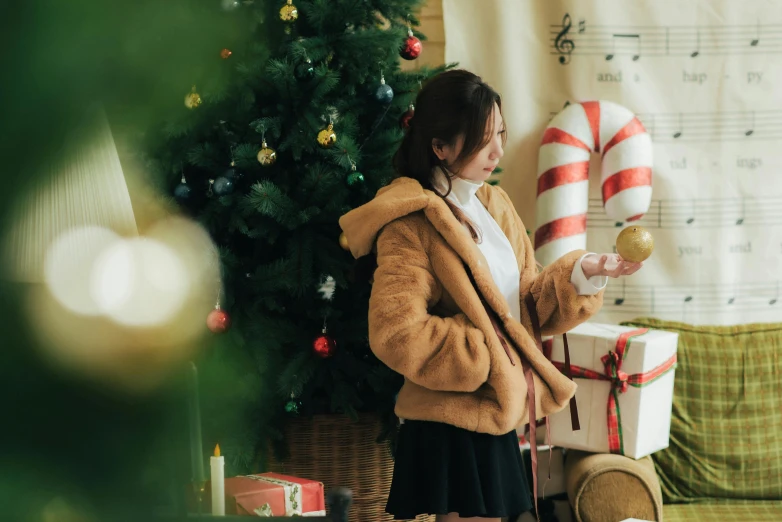 a woman standing in front of a christmas tree, pexels contest winner, brown clothes, japanese collection product, profile pic, indoor scene