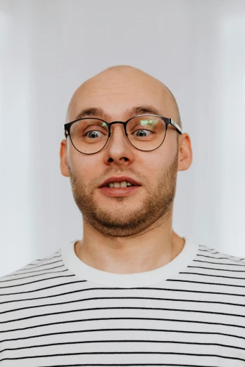 a bald man wearing glasses and a striped shirt, by Jóhannes Sveinsson Kjarval, featured on reddit, in front of white back drop, avatar image, mrbeast, ilya golitsyn