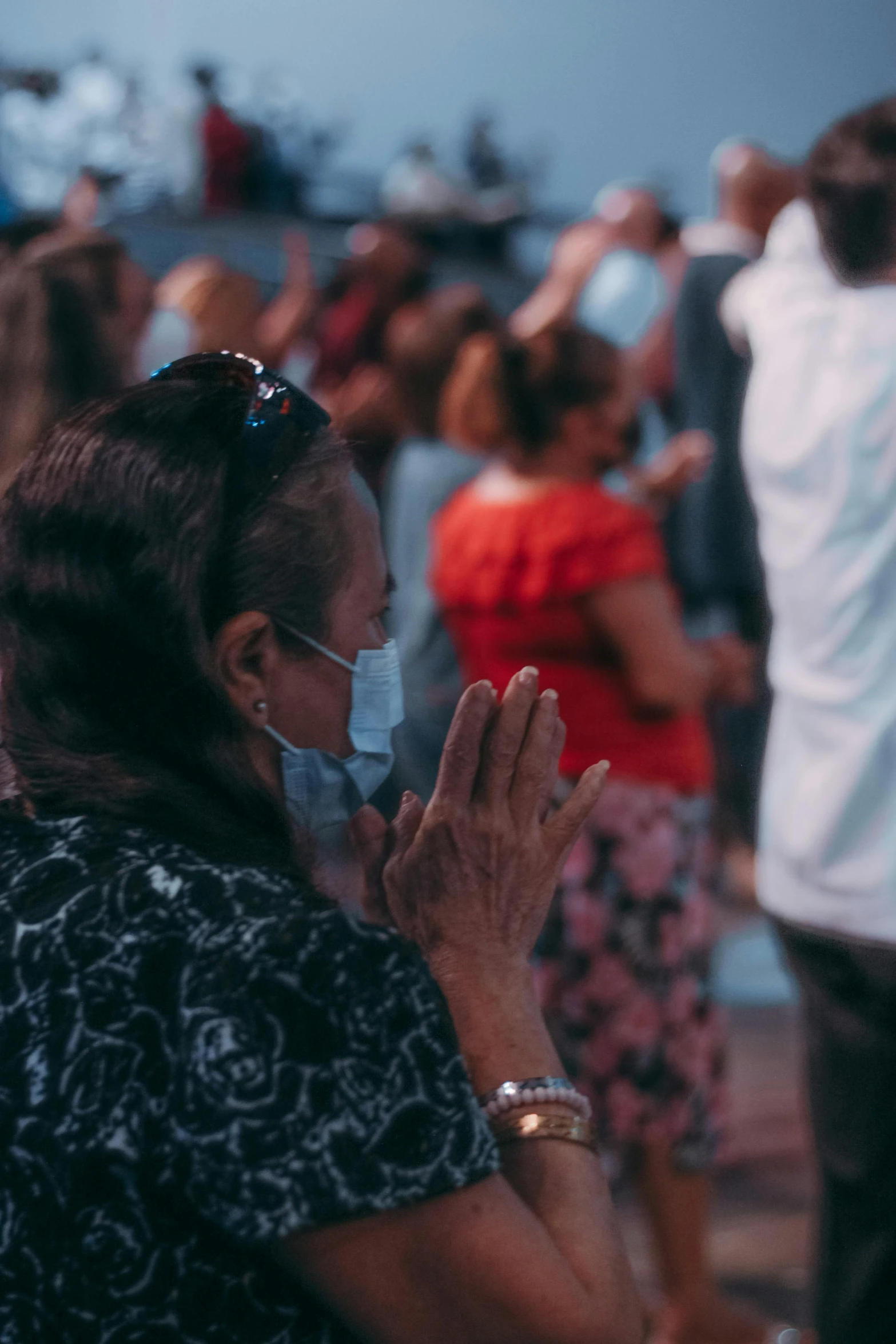 a woman wearing a face mask in front of a crowd of people, pexels, happening, praying posture, manila, screensaver, chilean