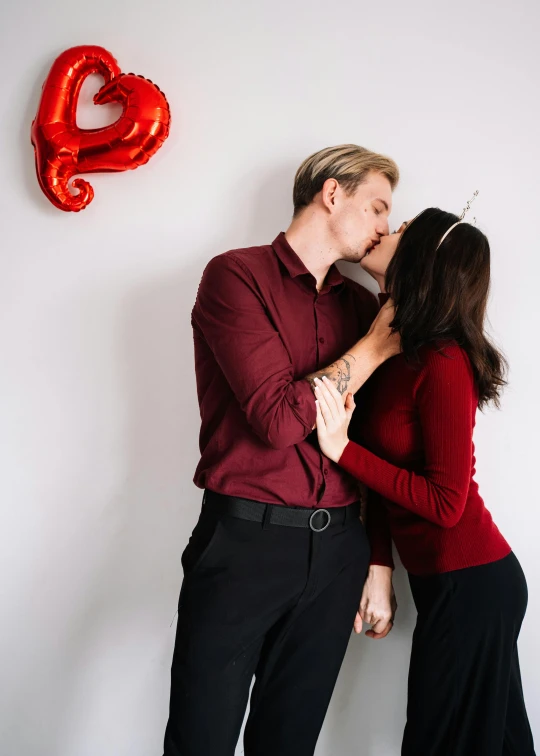 a man and woman kissing in front of a heart shaped balloon, by Julia Pishtar, pexels contest winner, red shirt brown pants, attractive man, platon, celebration