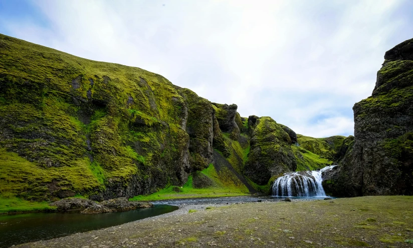 a waterfall in the middle of a lush green valley, by Julia Pishtar, pexels contest winner, hurufiyya, chiseled formations, near a small lake, conde nast traveler photo, highlands