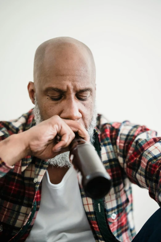 a man sitting on a couch with a microphone in his hand, inspired by William Grant Stevenson, pexels contest winner, process art, praying with tobacco, bald head and white beard, holding a bagpipe, black man