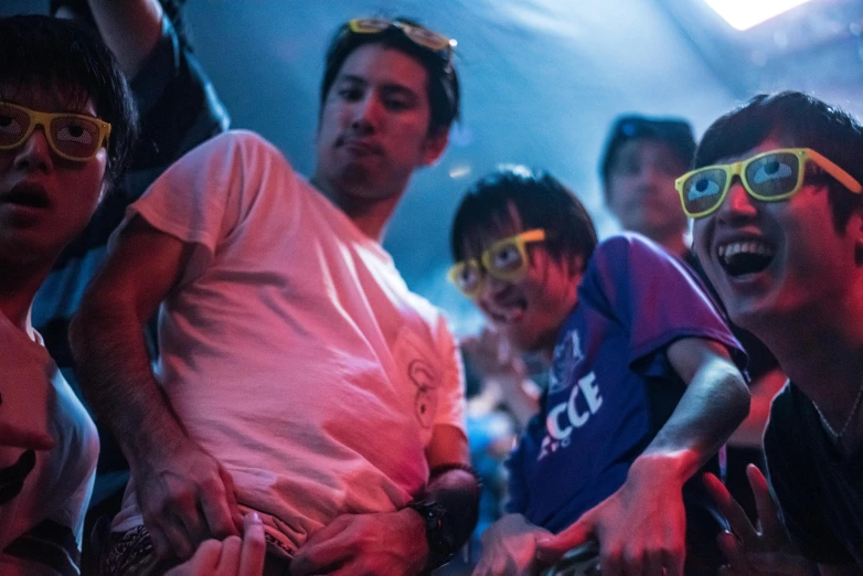 a group of young men standing next to each other, by Joe Bowler, reddit, happening, photograph of three ravers, wearing 3 d glasses, up close shot shinji aramaki, sitting down