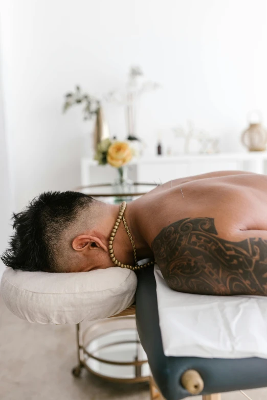 a man that is laying down on a bed, a tattoo, paradise garden massage, haze over the shoulder shot, connection rituals, profile image