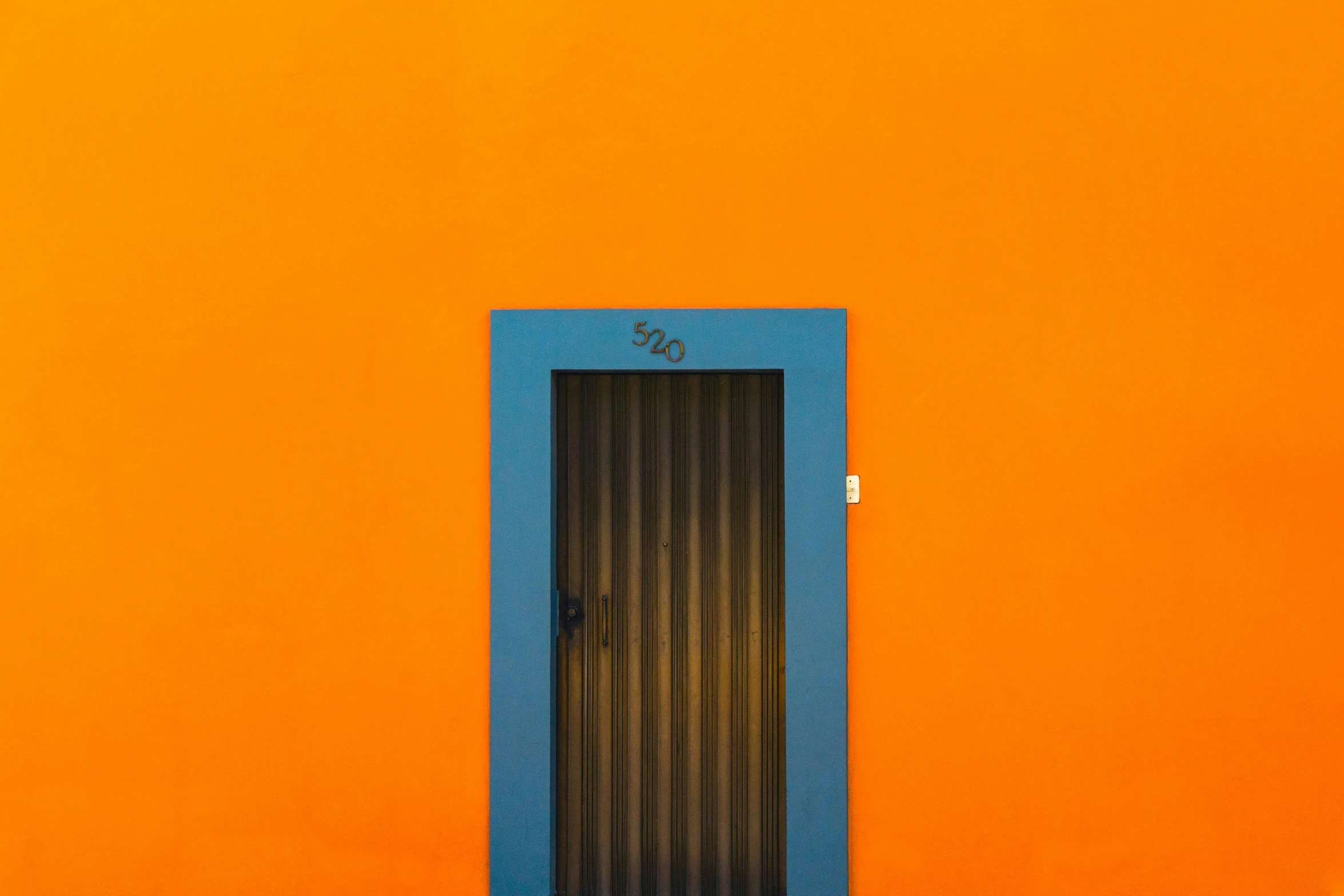 an orange building with a blue door in front of it, a minimalist painting, pexels contest winner, 🦩🪐🐞👩🏻🦳, magic doorway, black and orange, rectangle