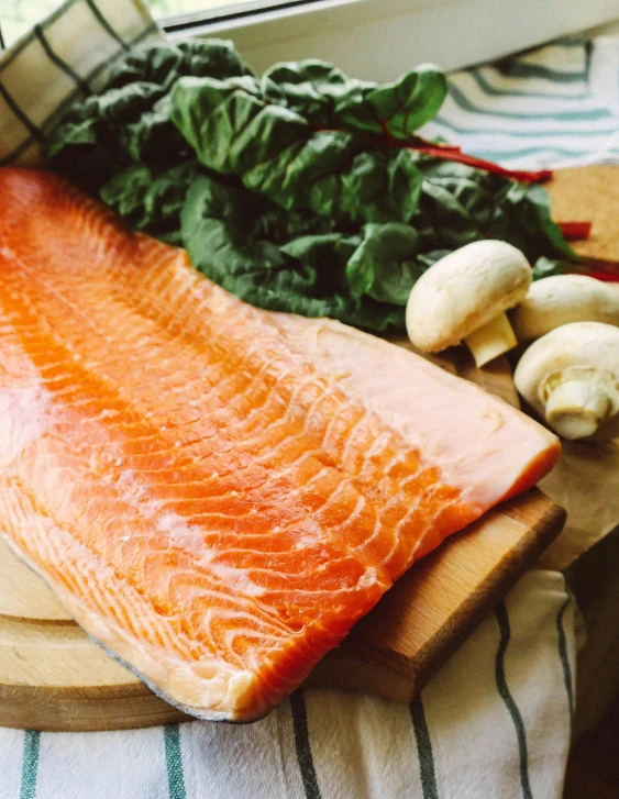 a piece of salmon sitting on top of a cutting board, by Jacob Burck, unsplash, multiple stories, greens), full faced, oh