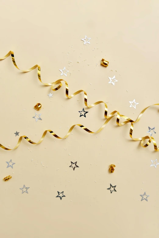 a cake sitting on top of a table covered in confetti, gold and silver shapes, shooting star, on high-quality paper, ribbon