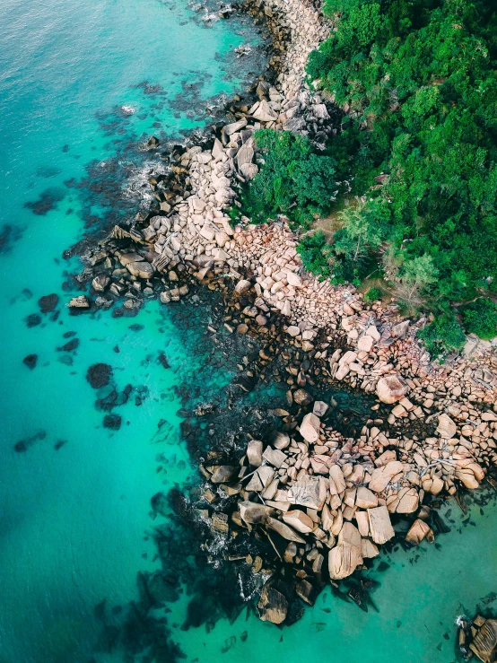 a large body of water next to a lush green hillside, by Seb McKinnon, pexels contest winner, tropical reef, flying rocky island, aerial view cinestill 800t 18mm, rocky beach