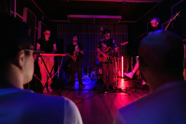 a group of people that are standing in a room, an album cover, unsplash, live performance, under light, in house, 3 band lineup