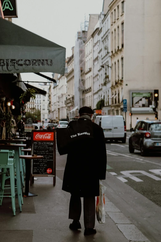 a man walking down a street holding an umbrella, standing in a restaurant, wearing a black hoodie, parisian buildings, facing away from the camera