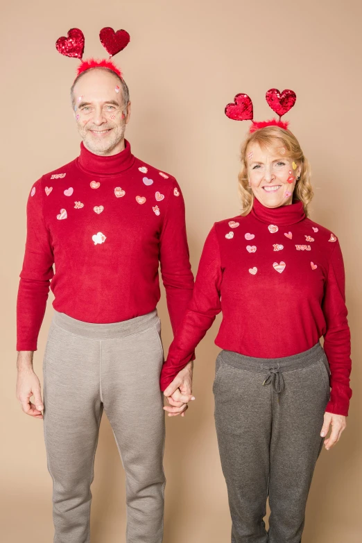 a man and a woman standing next to each other, a colorized photo, pexels, red sweater and gray pants, several hearts, frosting on head and shoulders, plain background