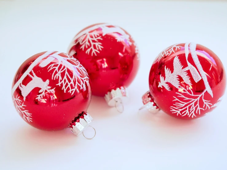 three red christmas ornaments sitting on top of a table, a photo, pexels, visual art, coral red, patterned, with a white background, opaque glass