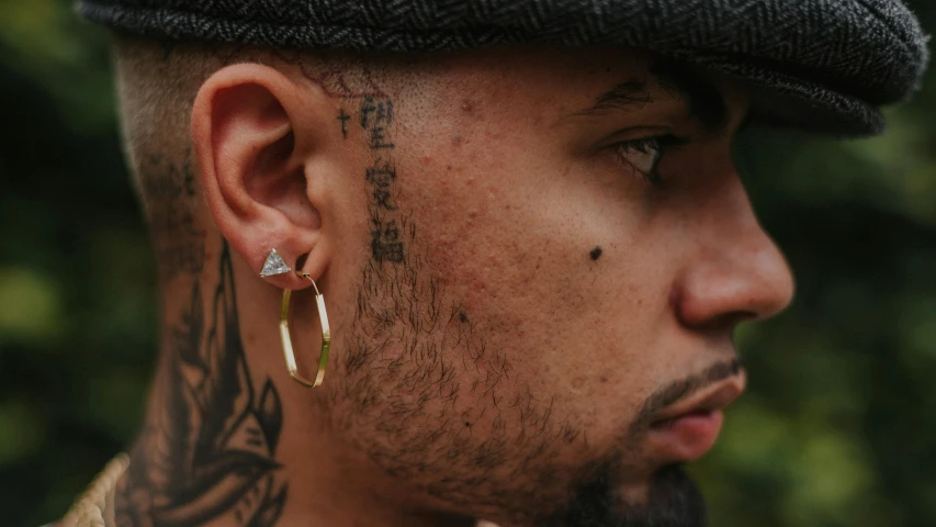 a close up of a person wearing ear piercings, an album cover, inspired by Christopher Williams, hyperrealism, gold line tattoos, rugged details, masculine features, threyda