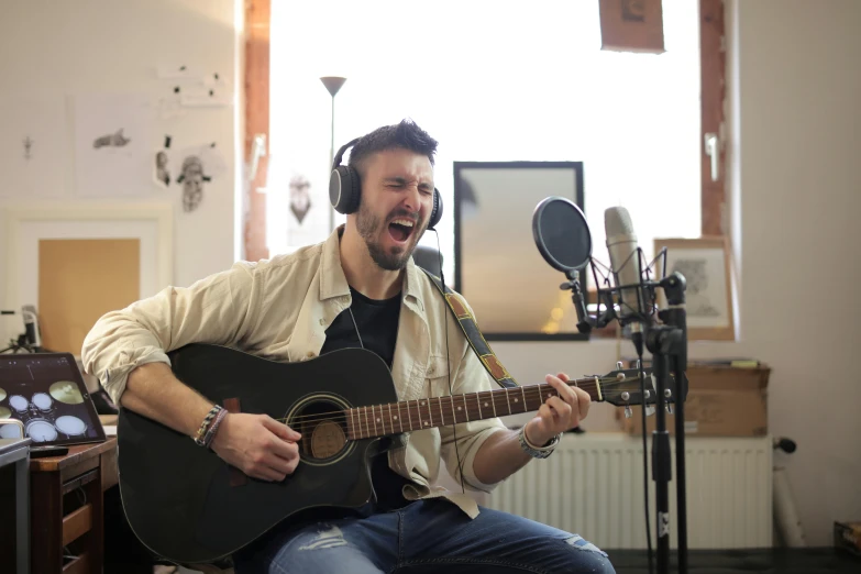 a man sitting in front of a microphone with a guitar, inspired by Niko Henrichon, pexels contest winner, smirking male bard, studio room, youtube thumbnail, raphael lecoste