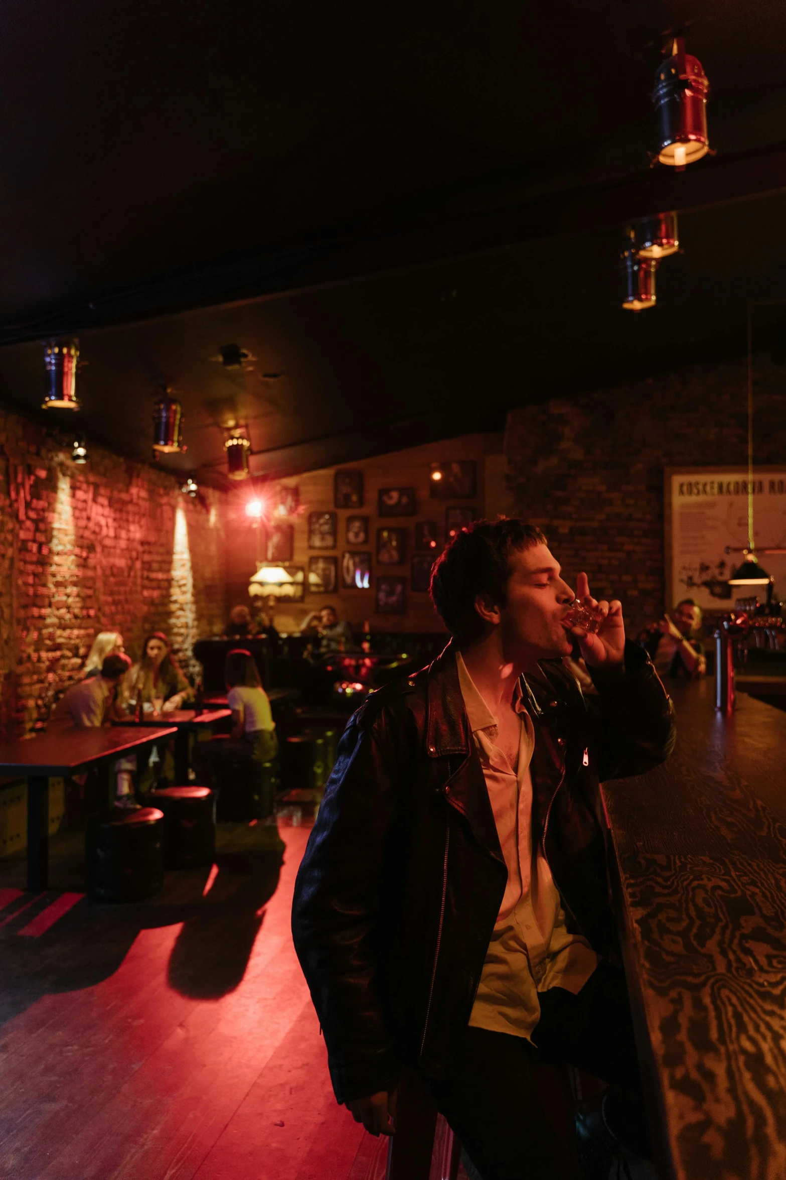 a man standing in front of a bar talking on a cell phone, an album cover, inspired by Nan Goldin, unsplash, happening, taking a smoke break, panoramic shot, whiskey, 2010s
