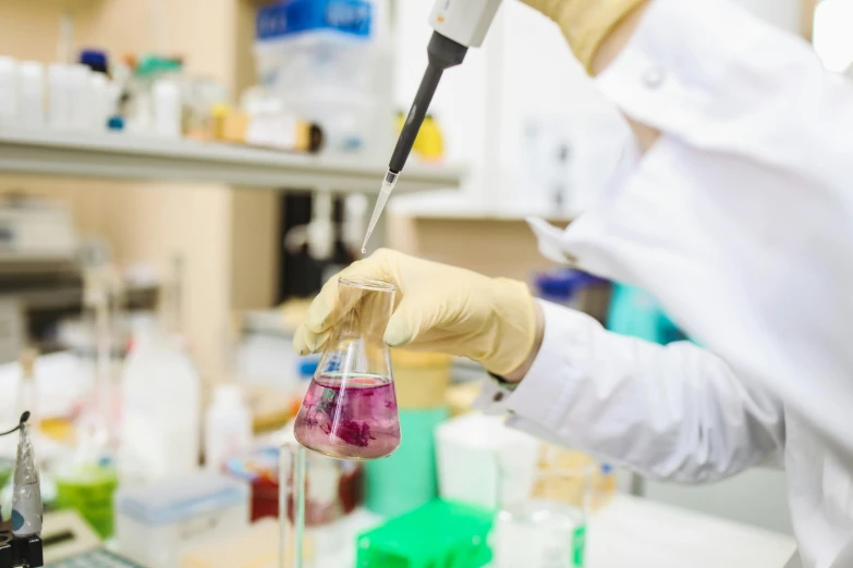 a person in a lab coat holding a tube filled with liquid, a picture, shutterstock, purple liquid, instagram photo, unedited, 278122496