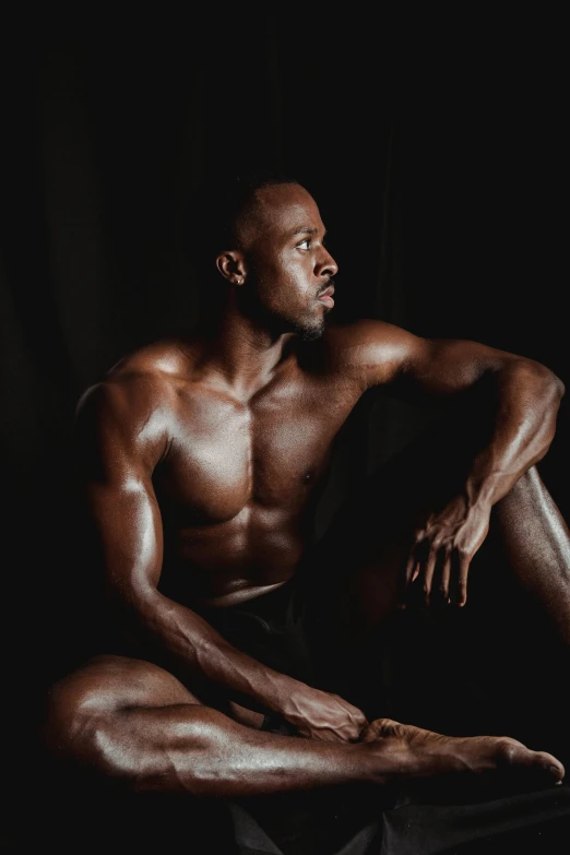 a man sitting on the floor with his legs crossed, by Jessie Alexandra Dick, pexels contest winner, bodybuilder physique, man is with black skin, fully chocolate, translucent skin