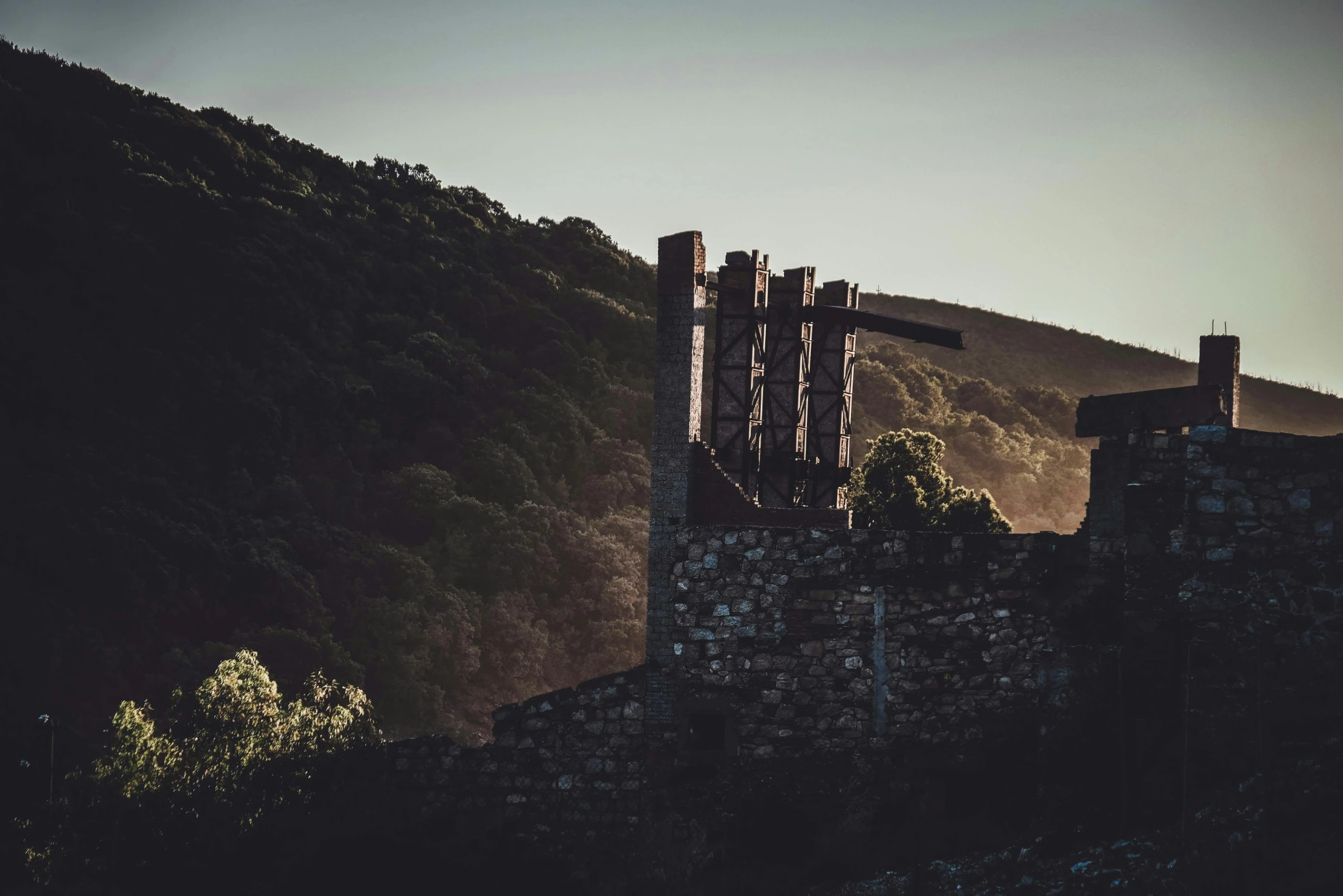 a castle sitting on top of a lush green hillside, by Kristian Zahrtmann, pexels contest winner, old lumber mill remains, dark warm light, brutalist style, morning glow