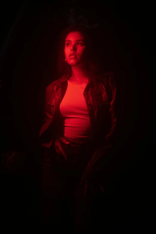 a woman standing in front of a red light, inspired by Nan Goldin, conceptual art, a portrait of lana del rey, powerful woman sitting in space, color film photography 1970s, in a claustrophobic