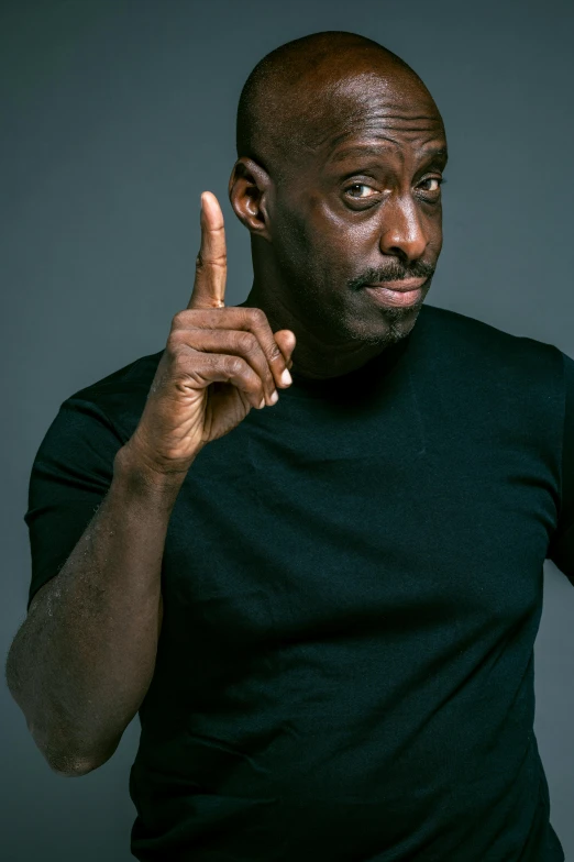 a man in a black shirt pointing at something, by David Begbie, lance reddick, standup comedian, promo photo, instagram photo