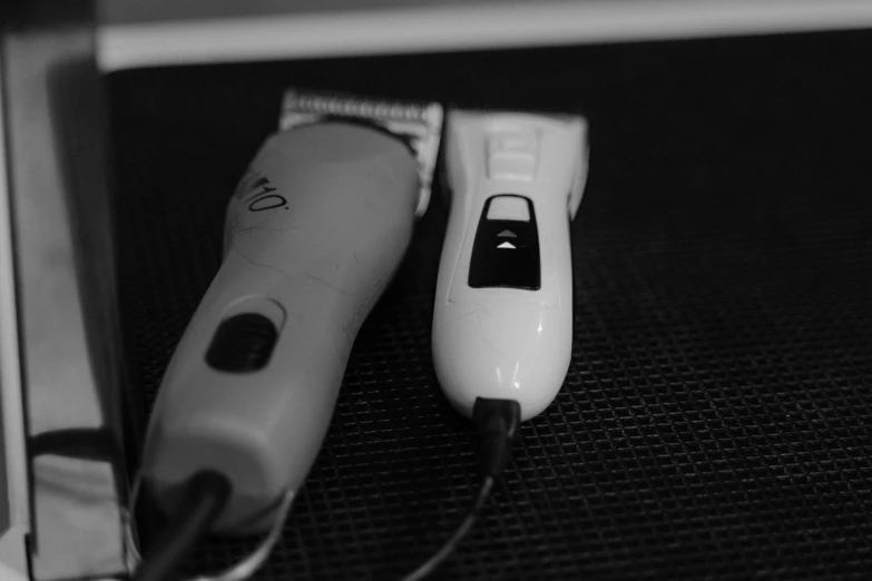two electric shavers sitting next to each other on a table, a black and white photo, by Amelia Peláez, diverse haircuts, hair are cable wires, ((sharp focus))