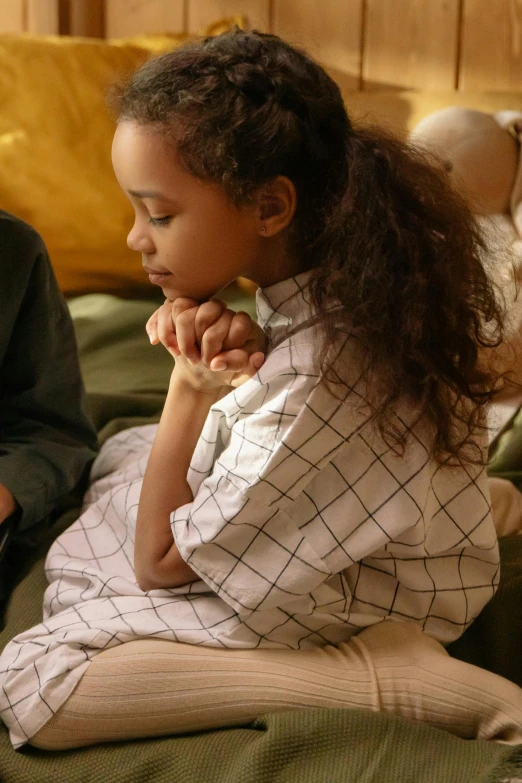 a couple of kids sitting on top of a bed, pexels, renaissance, praying posture, hand on her chin, light skinned african young girl, sitting on a couch