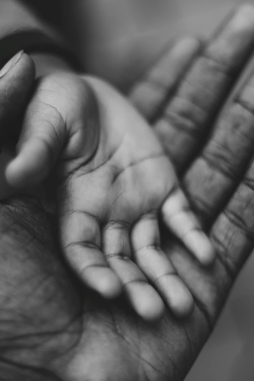 a black and white photo of a person holding a baby's hand, black man, open palm, uploaded, untitled