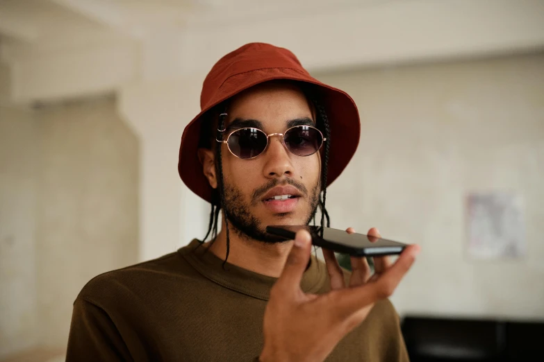 a man in a hat and sunglasses holding a cell phone, trending on pexels, visual art, ashteroth, looking to camera, high quality picture, uk